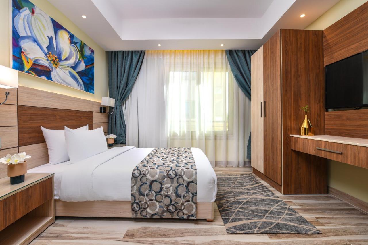 Tolip Resort El Galala Majestic Айн-Сохна Экстерьер фото The photo shows a well-designed hotel room. It features a comfortable bed with a decorative bedspread and two pillows. There are soft curtains framing a window that lets in natural light. On one side, there is a colorful piece of artwork hanging on t