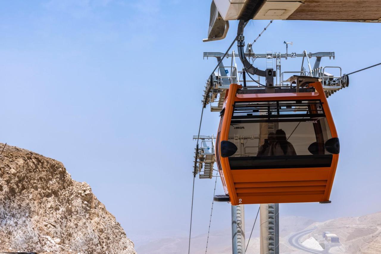 Tolip Resort El Galala Majestic Айн-Сохна Экстерьер фото The photo shows an orange gondola or cable car hanging on a cable system. The gondola appears to be suspended in the air above a rocky landscape, with a clear sky in the background. There are supporting cables and structures visible, indicating that 