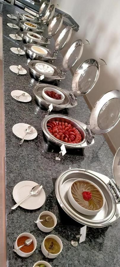 Tolip Resort El Galala Majestic Айн-Сохна Экстерьер фото The photo shows a buffet setup featuring multiple metal serving trays on a dark granite countertop. One tray contains circular slices of food, possibly sausages or a similar dish, while another bowl holds what appears to be red food items, though it'