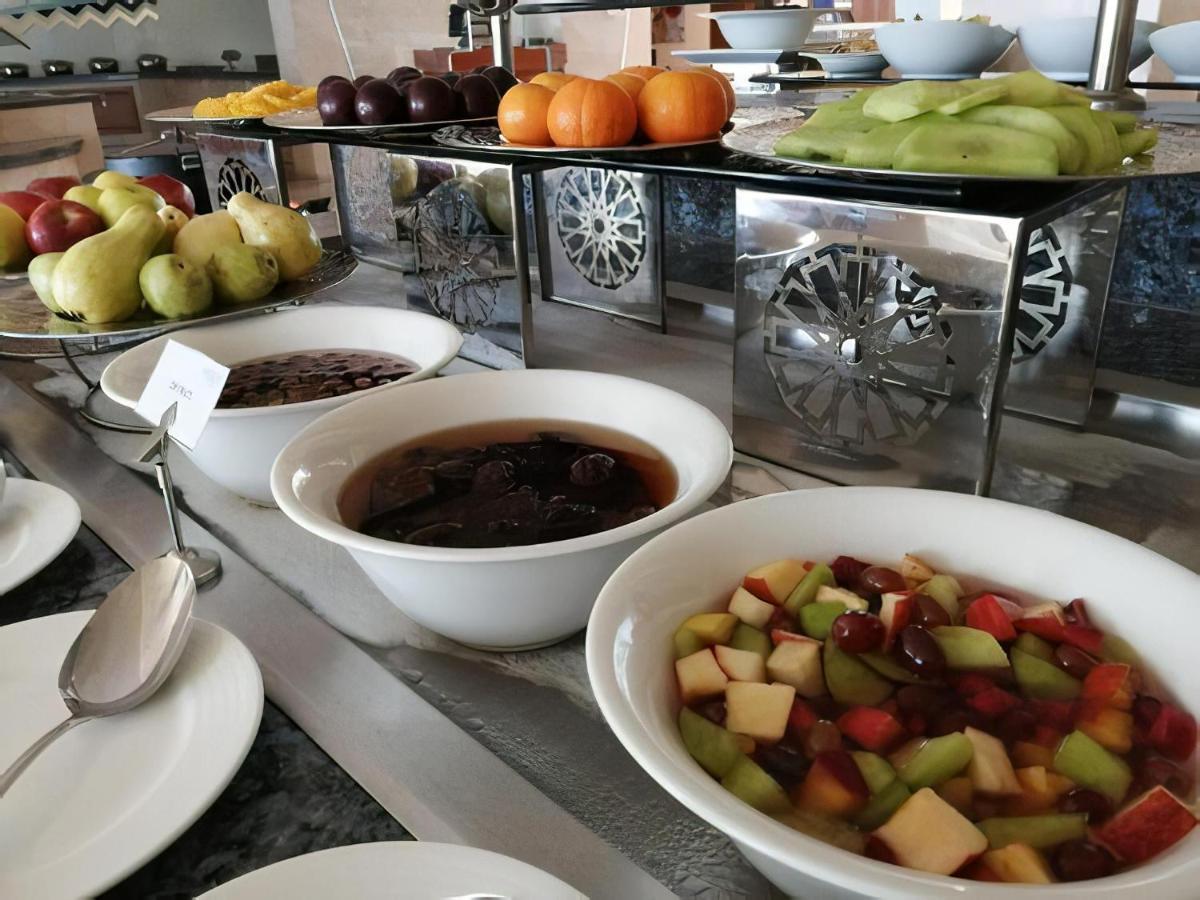 Tolip Resort El Galala Majestic Айн-Сохна Экстерьер фото The photo shows a buffet-style arrangement of various fruits and fruit dishes. In the foreground, there are several bowls containing different types of fruit. One bowl has a fruit salad made with diced apples, green apples, and possibly other fruits.